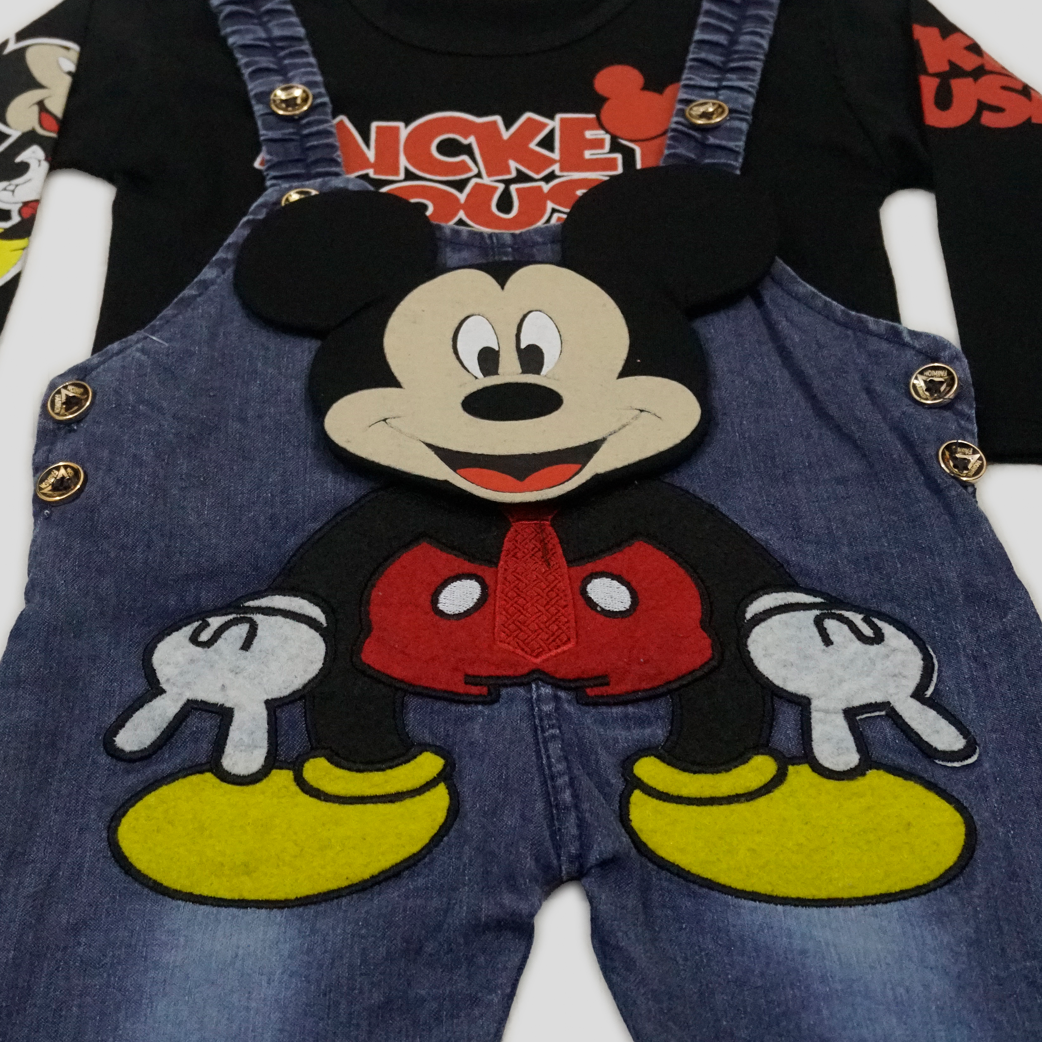 Two children wearing matching Mickey Mouse-themed outfits in a bright room.