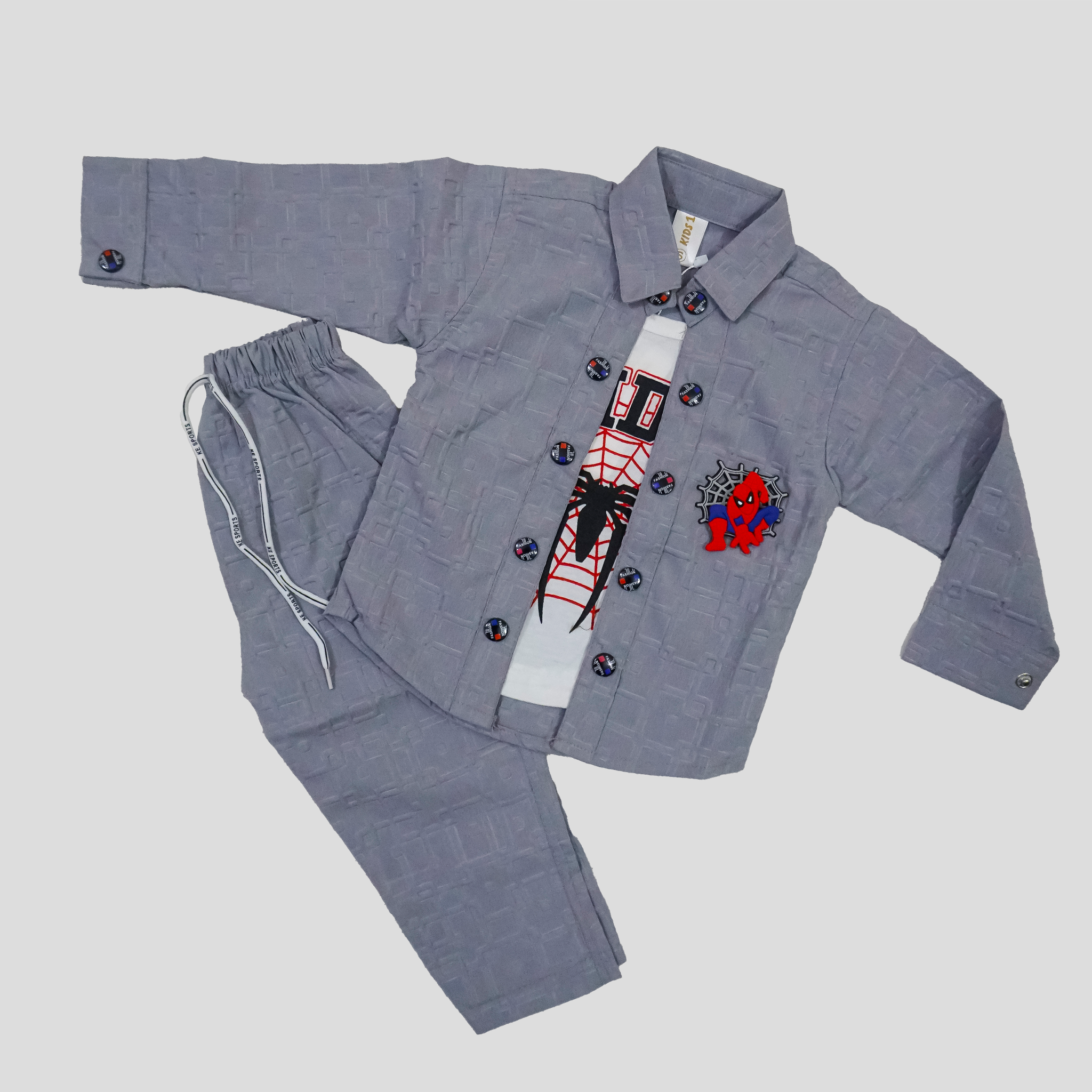 Child wearing a gray outfit with a colorful shirt in a room with white curtains and a bookshelf.