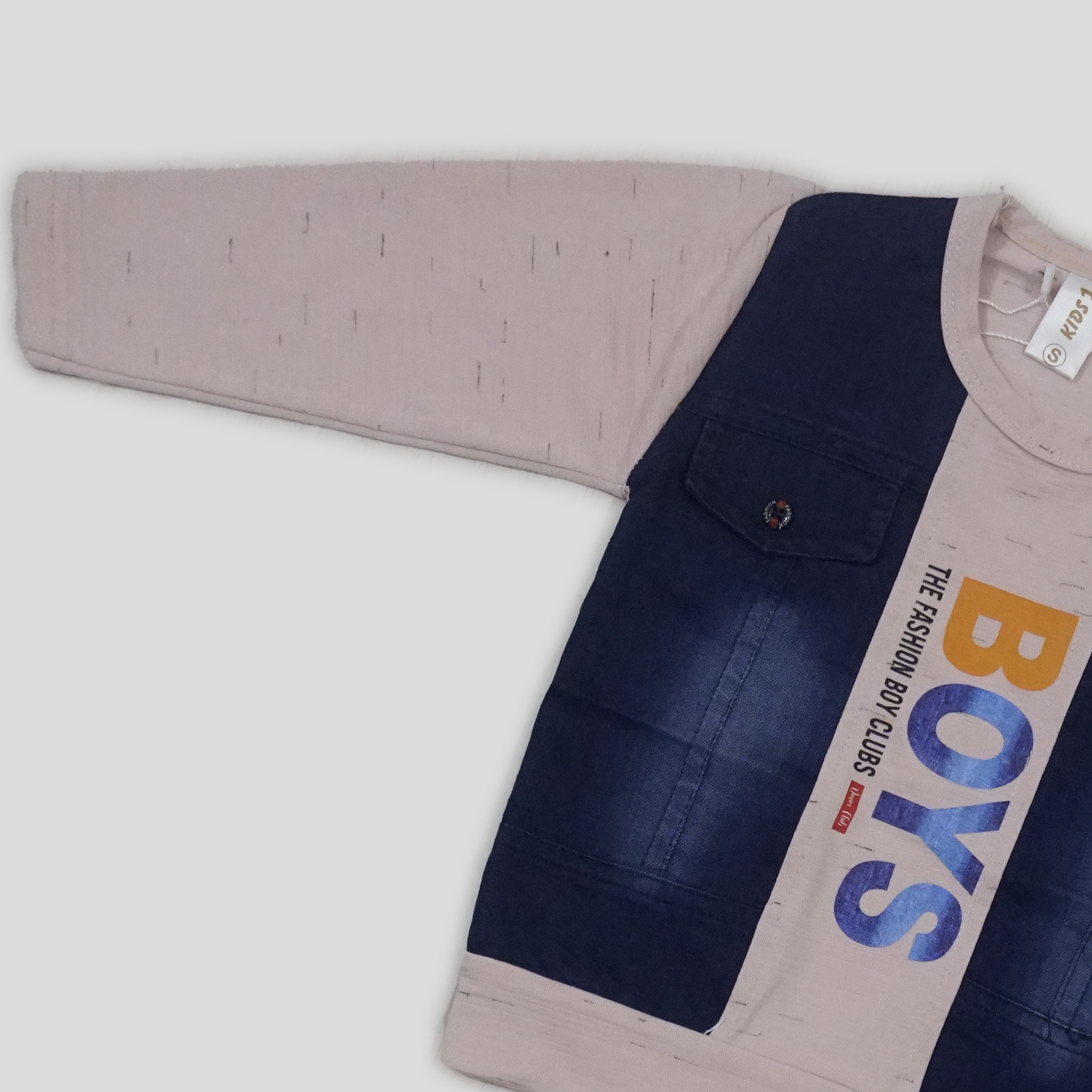 Child wearing a blue vest with 'BOYS' print, standing in a room with white curtains and a bookshelf.