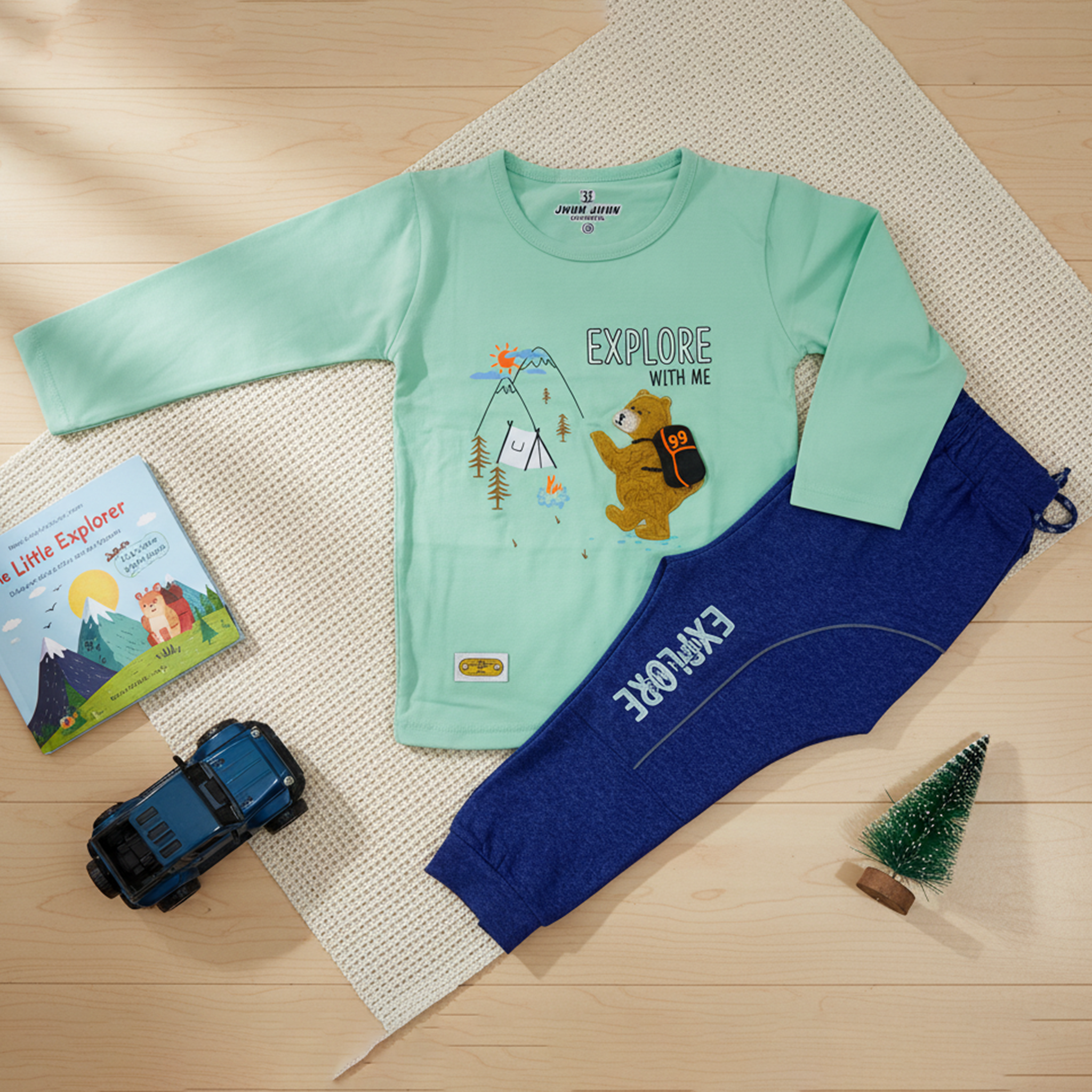 Child wearing a green long-sleeve shirt and blue pants with 'Explore' text, standing in a bright room.