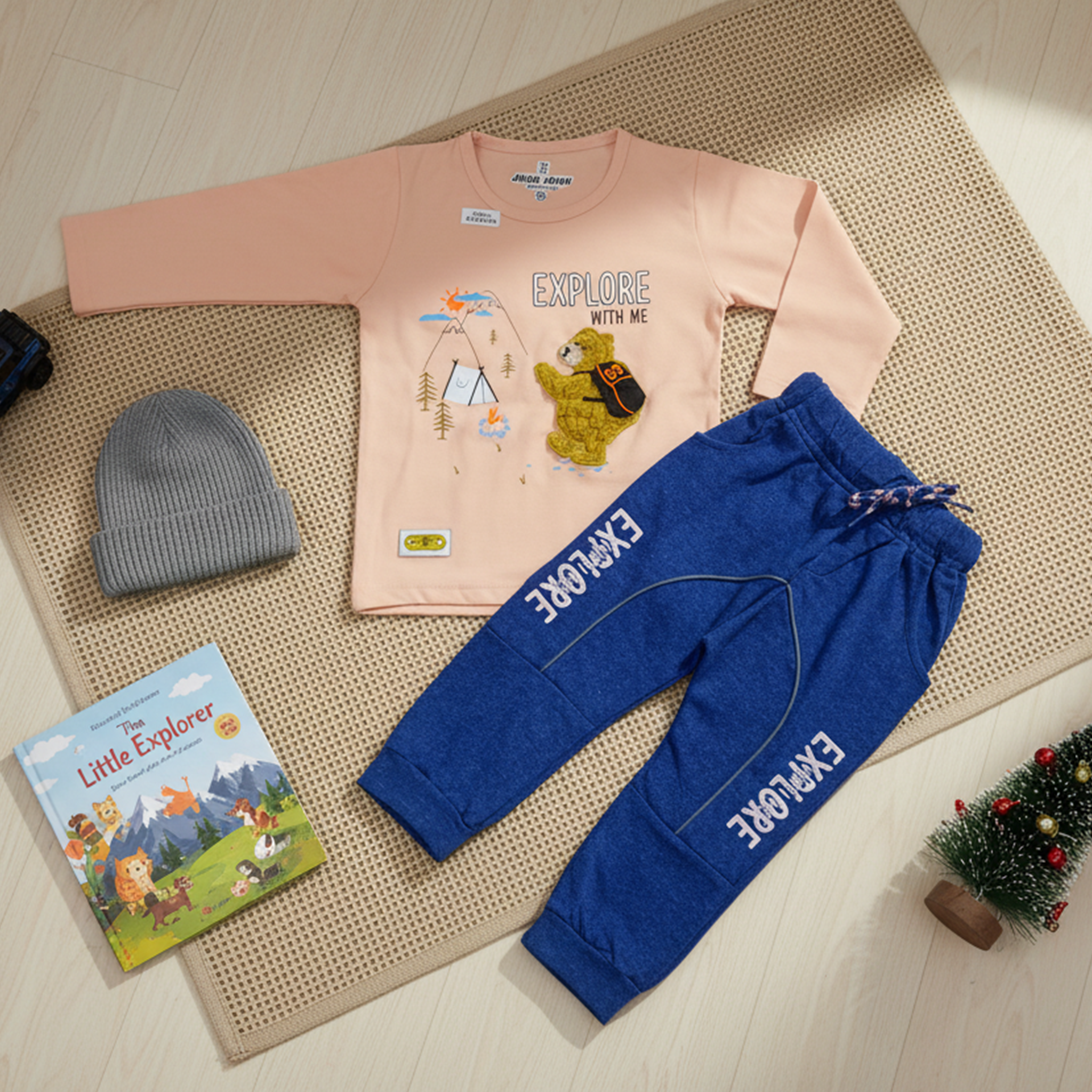 Child wearing a peach long-sleeve shirt and blue pants with 'EXPLORE' text, standing in a bright room.